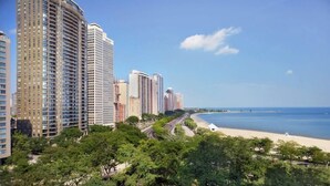 Un paisaje urbano costero con rascacielos, una playa y un paseo marítimo arbolado.