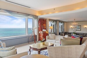 A hotel room with a large window offering a view of the ocean, a sofa, a coffee table, and a dining area with chairs. - 2 Connecting Suites at a 4⭐️ Hotel (Chicago)
