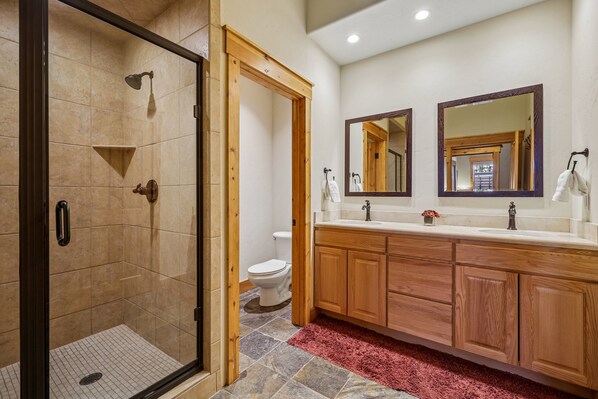 Une salle de bain avec une douche à parois de verre, des meubles en bois, un lavabo blanc et un miroir.