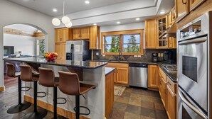 Una cocina moderna con armarios de madera, electrodomésticos de acero inoxidable y una isla central con taburetes de bar.