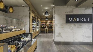 Un interior modern amb una paret de marbre, un rètol que diu 'MARKET' i una vitrina amb aliments.