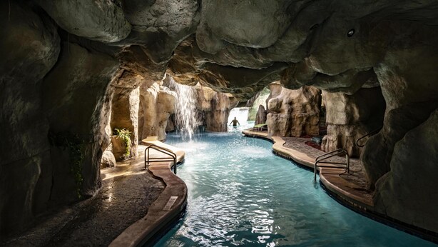 Una piscina interior amb cascada, envoltada de roques.