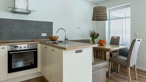 A modern kitchen with a built-in oven, a sink, and a wooden bowl on the countertop. - Vacation apartment Ritzhagen in Willingen (Willingen)