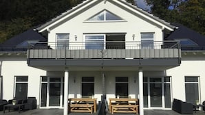 A two-story building with a balcony, large windows, and outdoor seating. - Vacation apartment Ritzhagen in Willingen (Willingen)