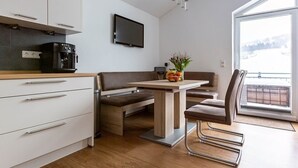Een moderne keuken met een eethoek, een flatscreen-tv en een groot raam met uitzicht.