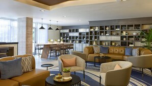 Un espace de vie moderne comprenant des canapés, des fauteuils, une table à manger et une bibliothèque.
