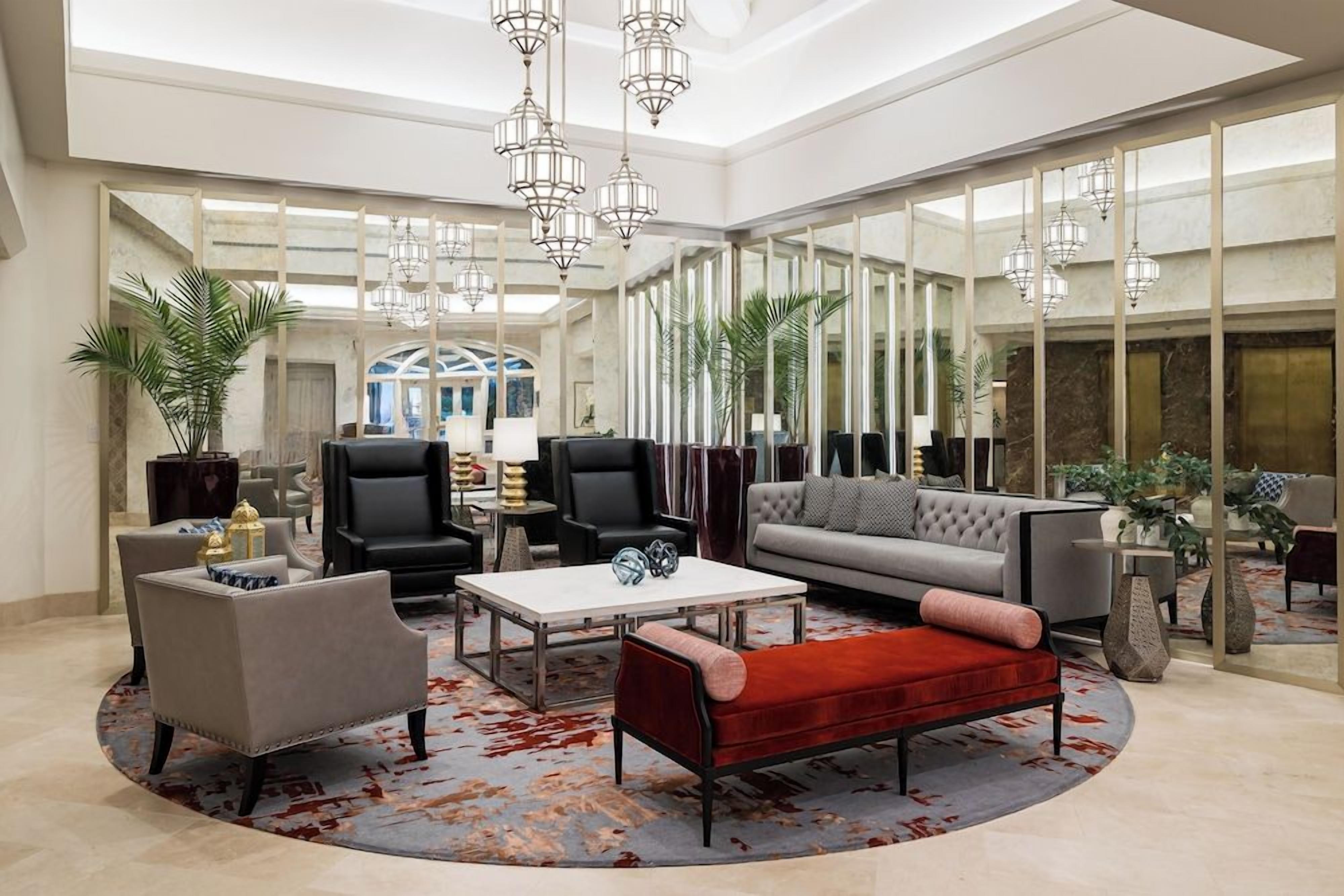 Eine geräumige Lobby mit hoher Decke, modernen Möbeln und großen Fenstern, die für viel Tageslicht sorgen.