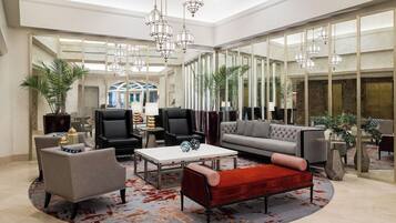 Eine geräumige Lobby mit hoher Decke, modernen Möbeln und großen Fenstern, die für viel Tageslicht sorgen.