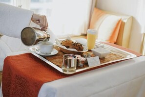 A breakfast tray with a cup, muffin, juice, and condiments on a bed. - 2 Connecting Suites at a 5⭐️ Hotel (San Francisco)