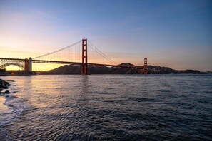 Eine Brücke über Wasser mit einem Sonnenuntergang im Hintergrund.