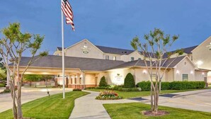 A hotel with a flagpole, a covered entrance, and a well-maintained lawn. - 2 Connecting Suites at a  Hotel (Houston)