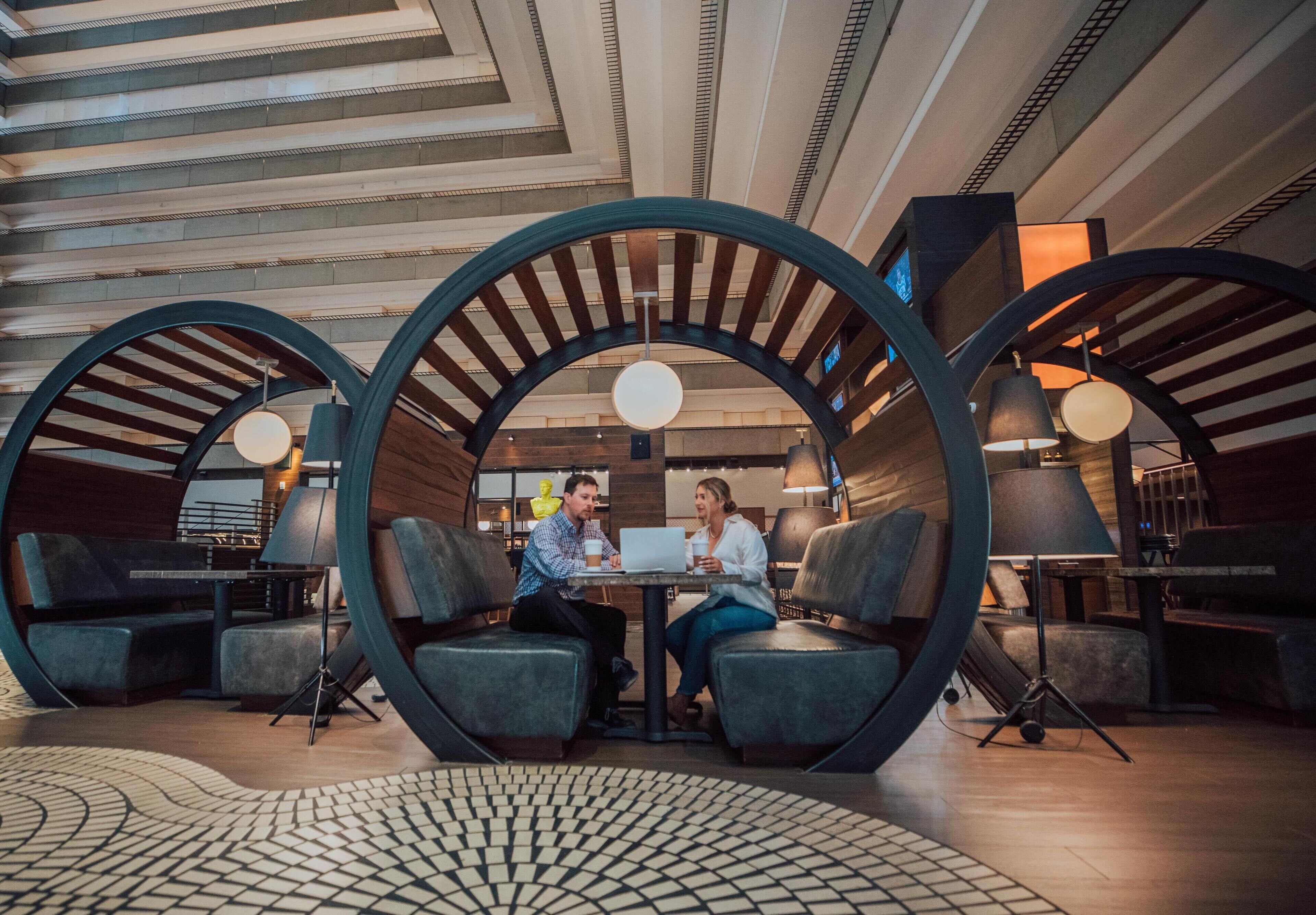 Ein modernes Interieur mit runden Sitzgelegenheiten, einem zentralen Tisch und einem gemusterten Boden.