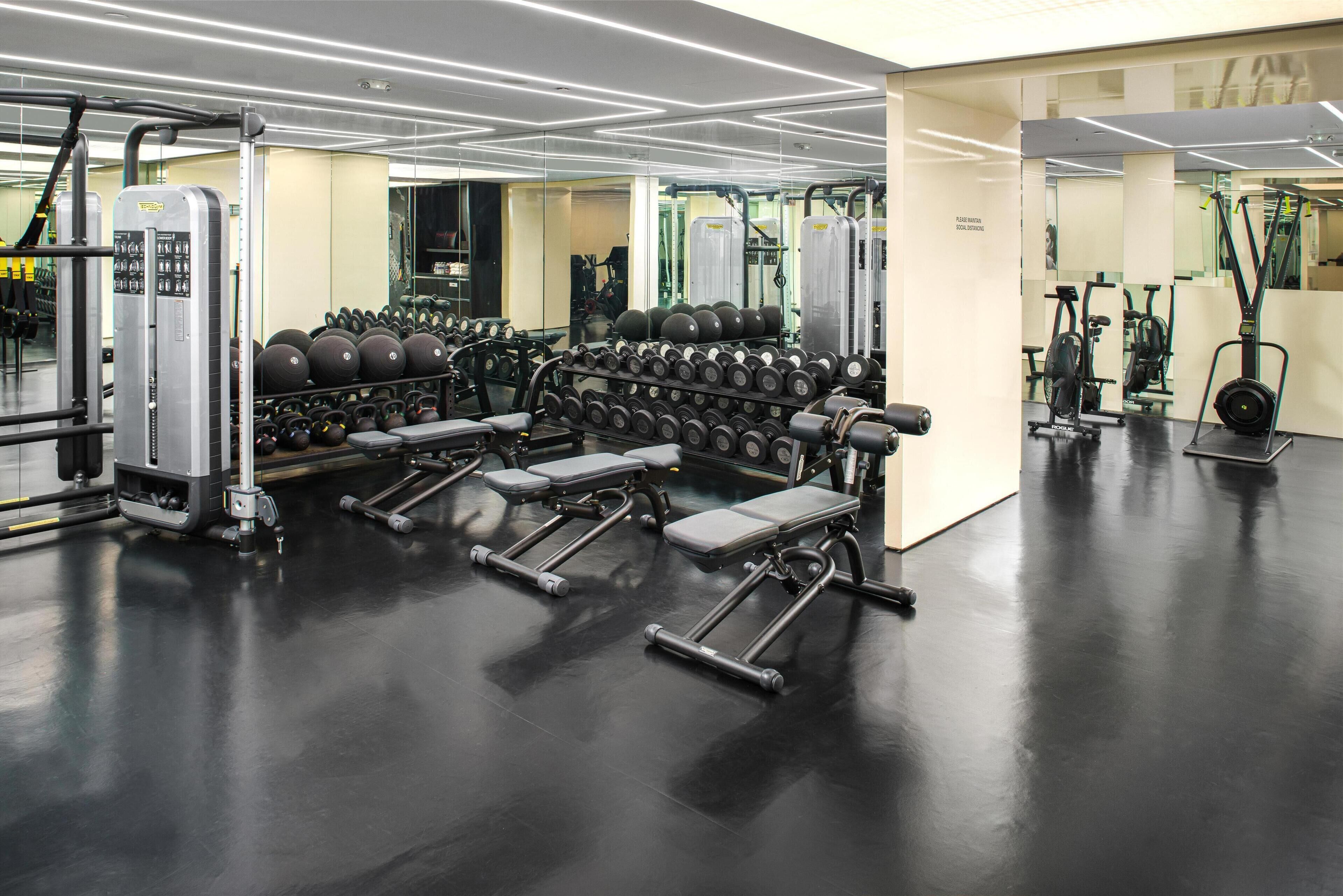 A gym with weight machines, dumbbells, and exercise balls.