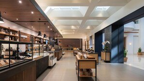 A modern interior with a bakery counter, seating area, and a view of the sky through the ceiling. - 2 Connecting Suites at a 4.5⭐️ Hotel (Orlando)