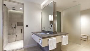 Ein modernes Badezimmer mit einer großzügigen Dusche, einem großen Spiegel und zwei Handtüchern.