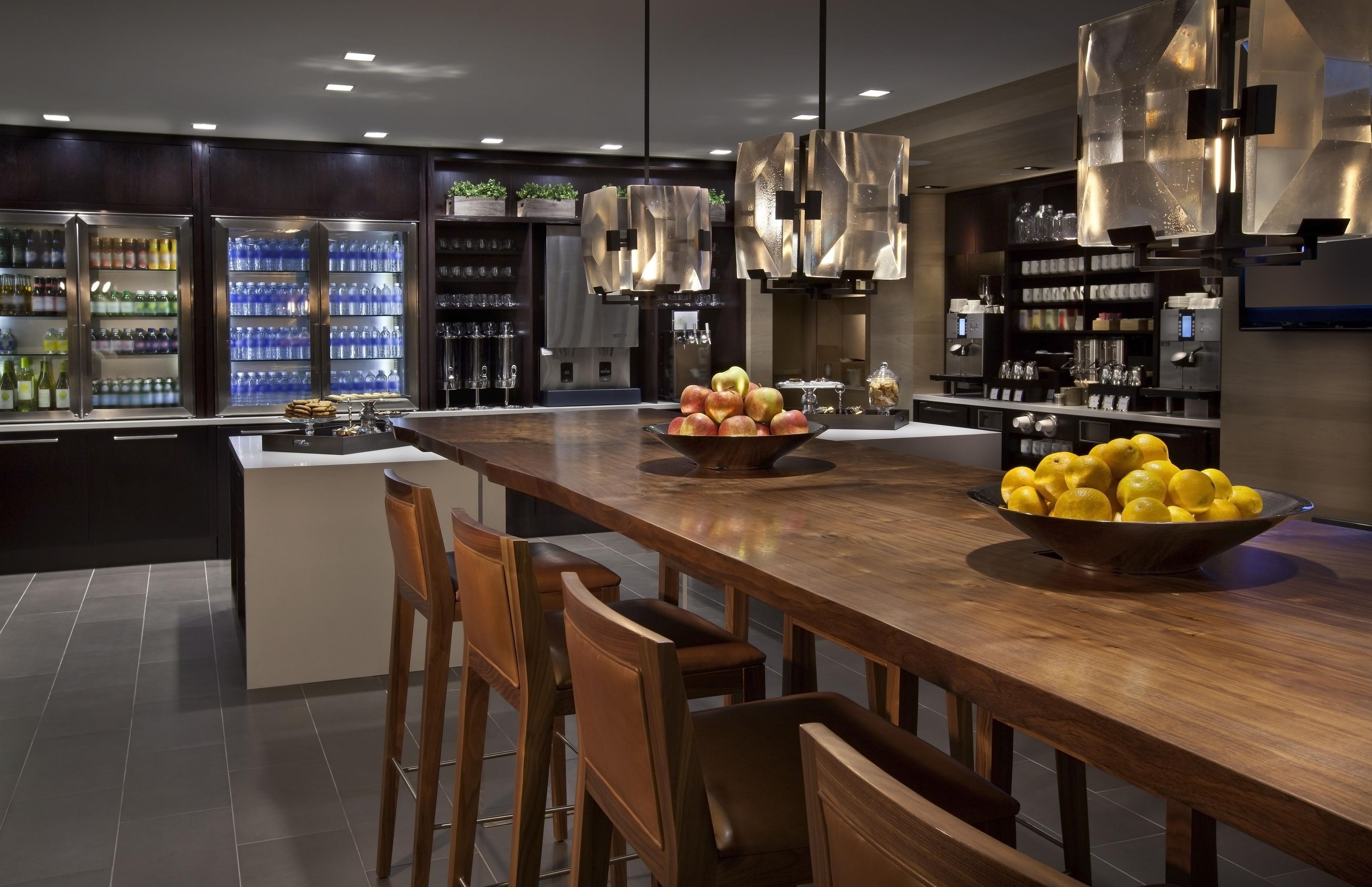 A modern kitchen with a central island, bar stools, and a variety of kitchen appliances.