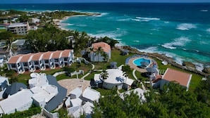 A resort with multiple white buildings, a swimming pool, and a view of the ocean. - OceanBlue (Inch Marlowe)
