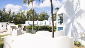 A resort with white buildings, palm trees, and a clear sky. - OceanBlue (Inch Marlowe)