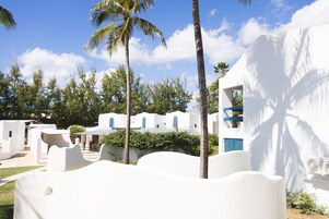 Un resort con edificios blancos, palmeras y un cielo despejado.