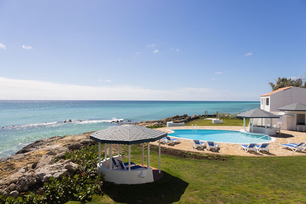Area piscina con gazebo, poltrone relax e vista sull'oceano.