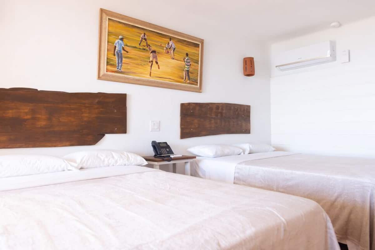 Ein Hotelzimmer mit zwei Betten, einem Bild an der Wand, einem Telefon und einer Klimaanlage.