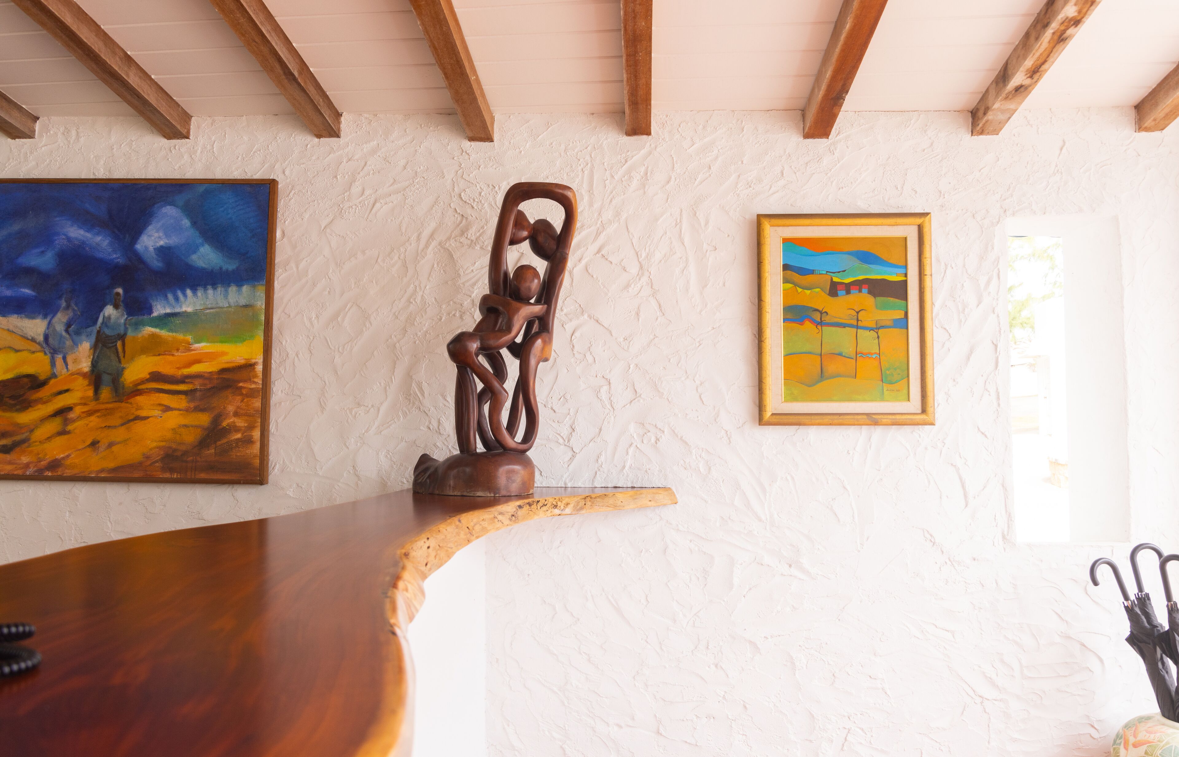 Ein Zimmer mit Holzboden, einer weißen Wand mit Struktur und zwei Gemälden.