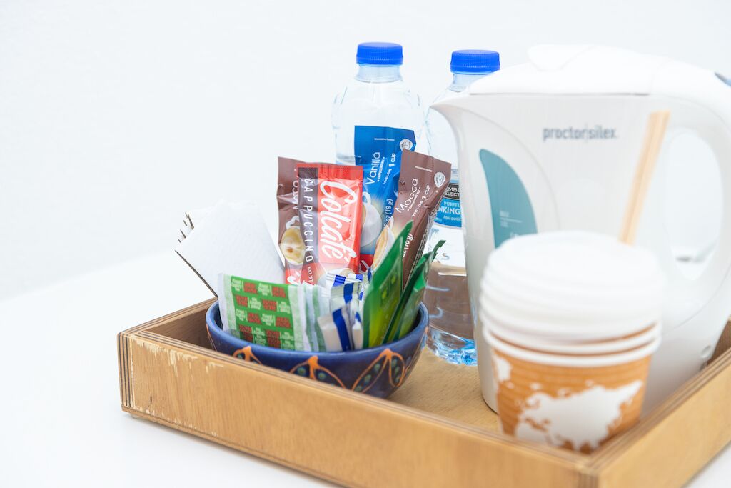 A tray with a coffee cup, a water jug, and various food items including snacks and a bottle of water.