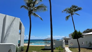 A resort with a pool, palm trees, and a view of the ocean. - OceanBlue (Inch Marlowe)