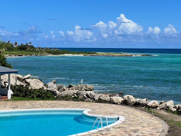 Un área de piscina con vistas al océano y a la costa rocosa.
