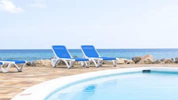 Una piscina al aire libre, sillones reclinables de piscina