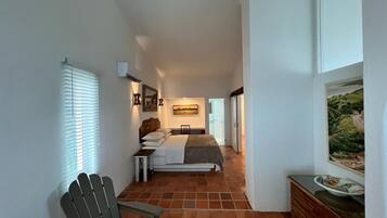 Un dormitorio con cama, una silla, un aparador y un cuadro en la pared.