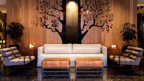 A modern lobby with a central sofa, two armchairs, and a coffee table.