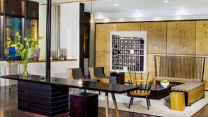 A modern interior with a dark wooden desk, a seating area with a cushioned bench, and a large abstract wall art piece. - 2 Connecting Suites at a 4⭐️ Hotel (Savannah)