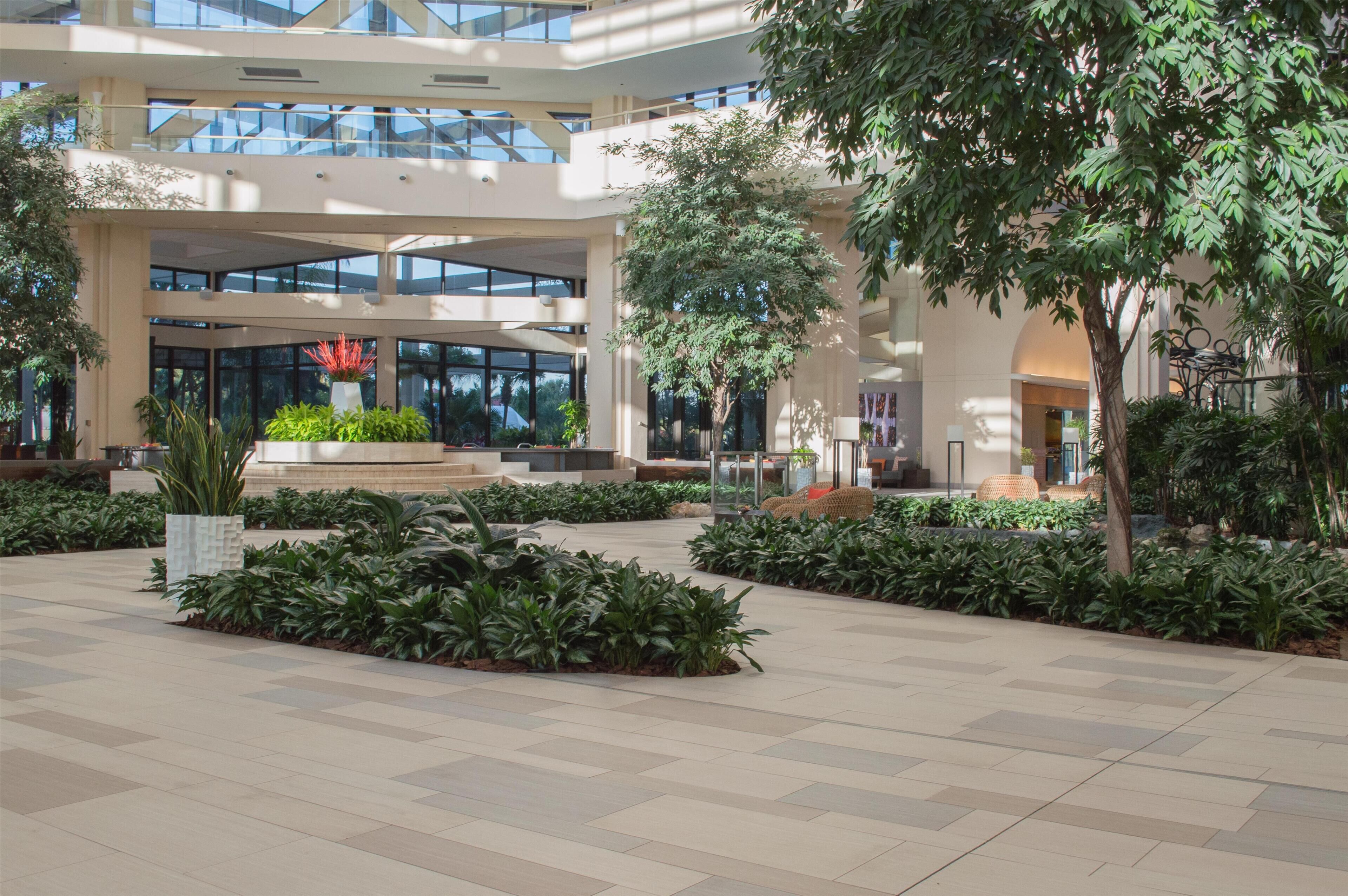 A spacious indoor atrium with a central garden, multiple levels, and large windows.
