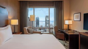 A hotel room with a large bed, a desk, a chair, and a view of the cityscape. - 2 Connecting Suites at a 4.5⭐️ Hotel (Seattle)