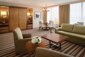 A hotel room with a striped carpet, a sofa, a dining table with chairs, a coffee table, and a large wardrobe. - 2 Connecting Suites at a 4.5⭐️ Hotel (Orlando)