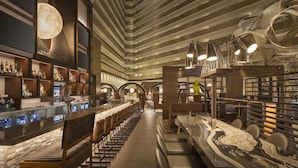 A modern bar area with a long counter, seating, and a unique ceiling design.
