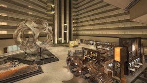 A spacious lobby with a large metallic sculpture, multiple seating areas, and a modern design.
