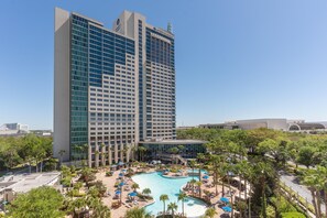 Un hôtel de grande hauteur doté d’une piscine, de palmiers et surplombant un ciel d’un bleu limpide.