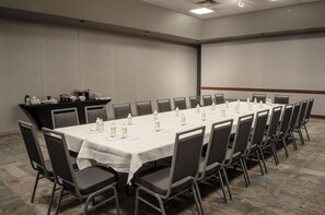 A conference room with a long table, chairs, and a buffet area with food and drinks. - 2 Connecting Suites at a  Hotel (Fargo)