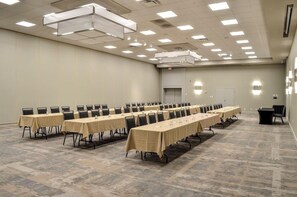 Une salle de conférence dotée de plusieurs tables, de chaises et d’un sol recouvert de moquette.