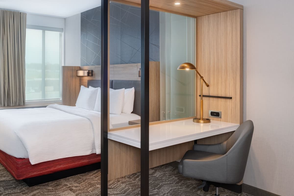 Ein modernes Hotelzimmer mit einem Bett, einem Schreibtisch und einem Stuhl.