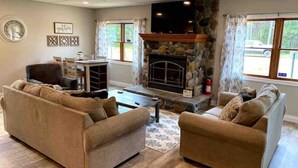 A living room with a stone fireplace, two sofas, a coffee table, and a TV.