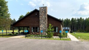 A lodge with a stone chimney, wooden exterior, and a covered porch area.
