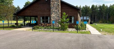 A lodge with a stone chimney, wooden exterior, and a covered porch area.