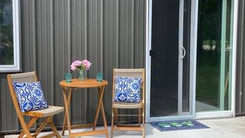 Une terrasse avec deux chaises en bois, une petite table ronde et un vase rempli de fleurs.