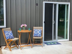 A patio with two wooden chairs, a small round table, and a vase with flowers. - Fairway Lodge-Rome Away From Home-5min Sand Valley (Nekoosa)