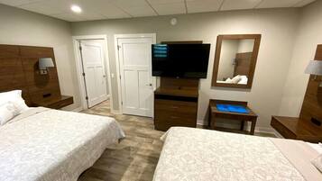 A hotel room with two beds, a TV, a mirror, a desk, and a wardrobe.