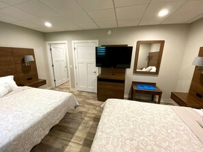 A hotel room with two beds, a TV, a mirror, a desk, and a wardrobe. - Fairway Lodge-Rome Away From Home-5min Sand Valley (Nekoosa)