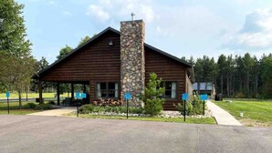 A lodge with a stone chimney, wooden exterior, and a covered porch area.